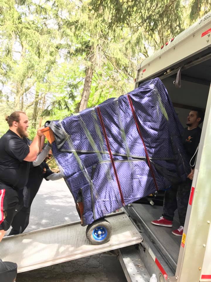 Coyne's Moving crew loading a wrapped piece of furniture onto a truck